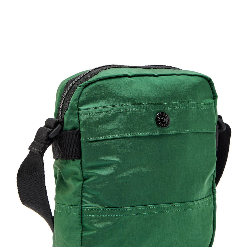 Green crossbody bag with black straps on a white background